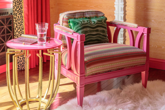 Pink armchair with striped cushions and gold and pink side table