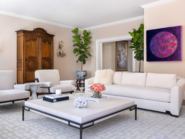 Kimberley Harrison's modern living room with white couch, coffee table, and accent chairs is offset with an antique French armoire and crystal sconces 