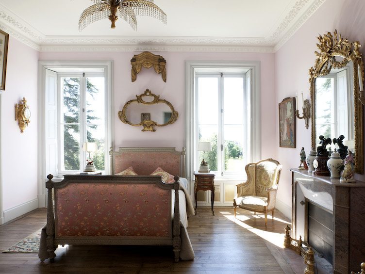 Light pink bedroom with brass wall hangings and pink upholstered bed