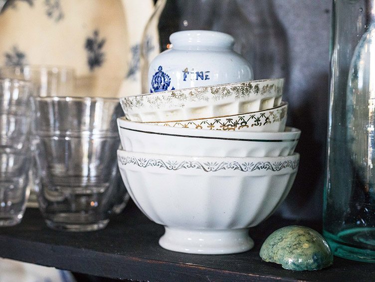 Stack of Vintage Bowls on black wood shelf with glasses and bottle