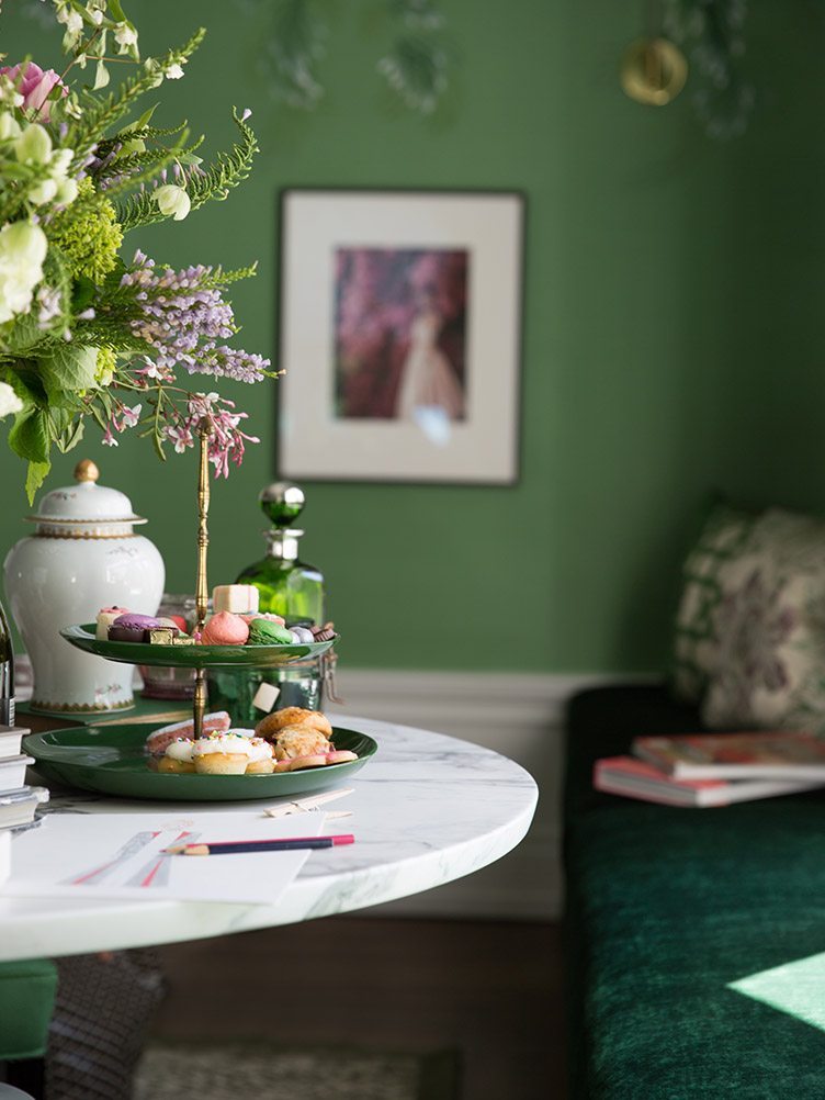 Assorted pastries and decor on white on white marble table in a green room.