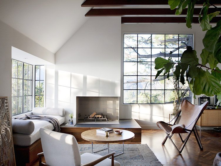 Contemporary living room with large windows, a butterfly chair, and neutral colors.