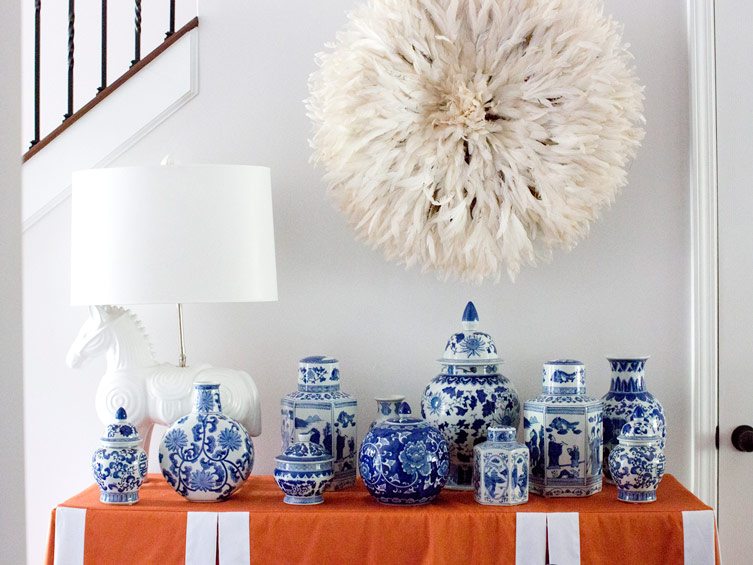 Side table with blue and white jars and vases under a white hanging juju hat