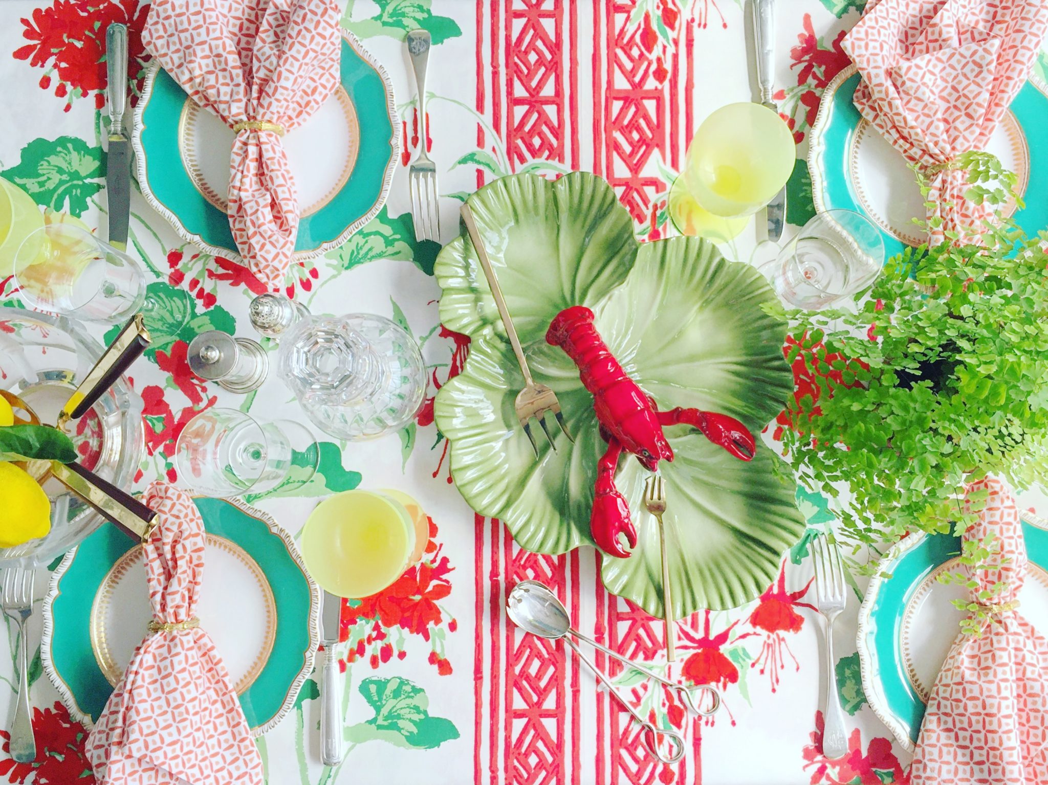 Maximalist table scape with leaf plate and aqua-rimmed plates with floral tablecloth