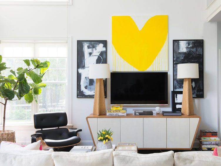 White sofa in front of black accent chair and wooden tv stand with twin buffet lamps