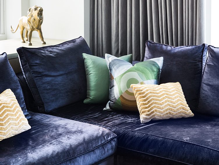 Blue velvet sectional with gold lion statue and assorted throw pillows