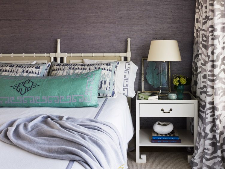 Bedroom with Lavender Bed Blankets and Monogrammed Pillow Next to White Bedside Table.