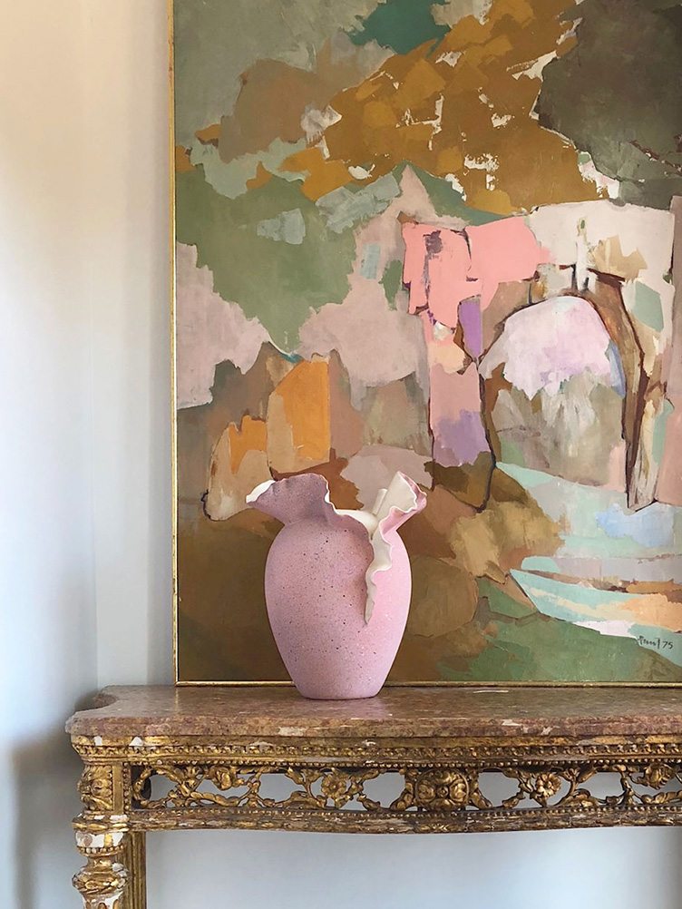 Distressed gold side table with abstract painting and pink ceramic vase