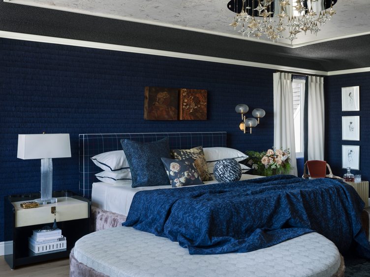 Bedroom with blue textile wallpaper and matching blue bed and textiles.