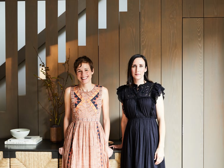 Amanda Jesse and Whitney Parris-Lamb of Interior Design Company Jesse Parris-Lamb stand in front of modern wood staircase.