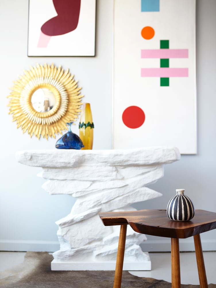 White plaster sculptural side table with colorful paintings and round mirror