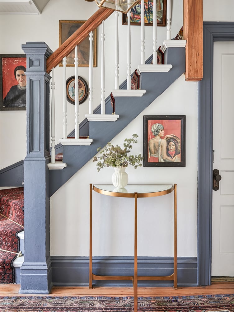 Shabby Chic Home Entryway with Blue Staircase and Collection of Vintage Paintings. 