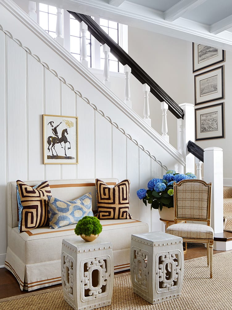 Traditional Home Entryway with White Sofa, Patterned Pillows, and Hanging Art.