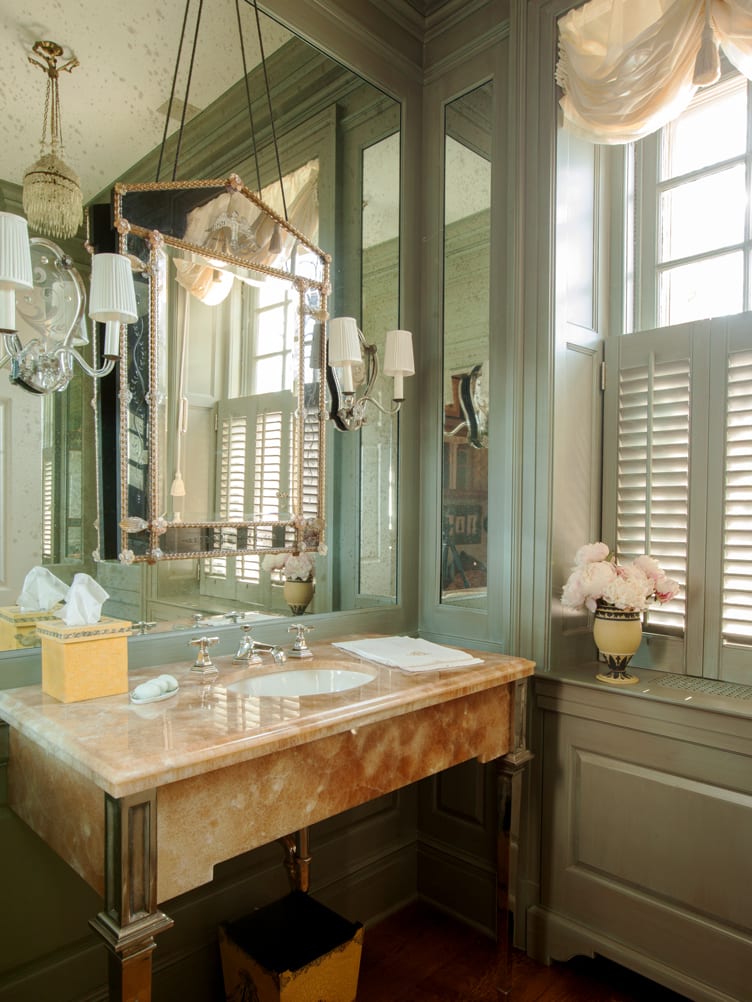 Green-gray bathroom with large mirrors and orange marble sink.