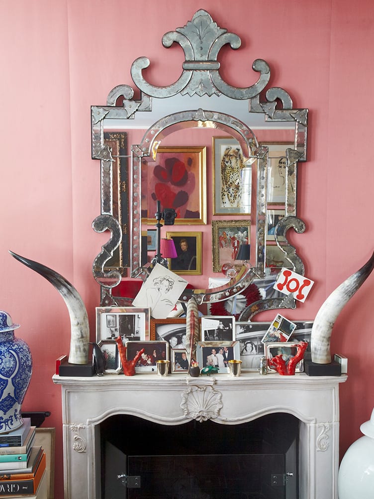 Eclectic Fireplace Mantle with Animal Tusks, Collection of Family Photographs, and Large Mirror.