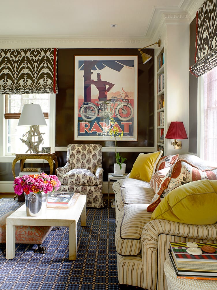 Striped sofa, light brown wooden coffee table, leaf patterned armchair, and vintage poster in living room