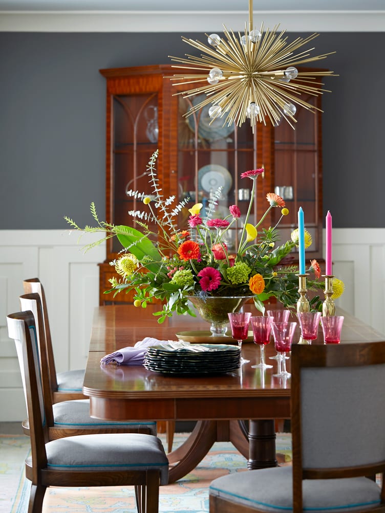 Dining room with starburst chandelier and classic wood dining table with chairs and wood display case.