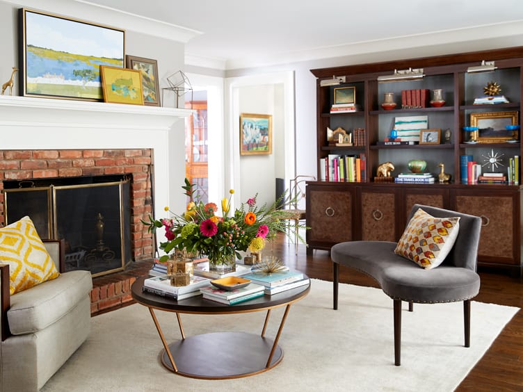 Living room with mid-century style love seat, round coffee table, and wooden sideboard and shelves.