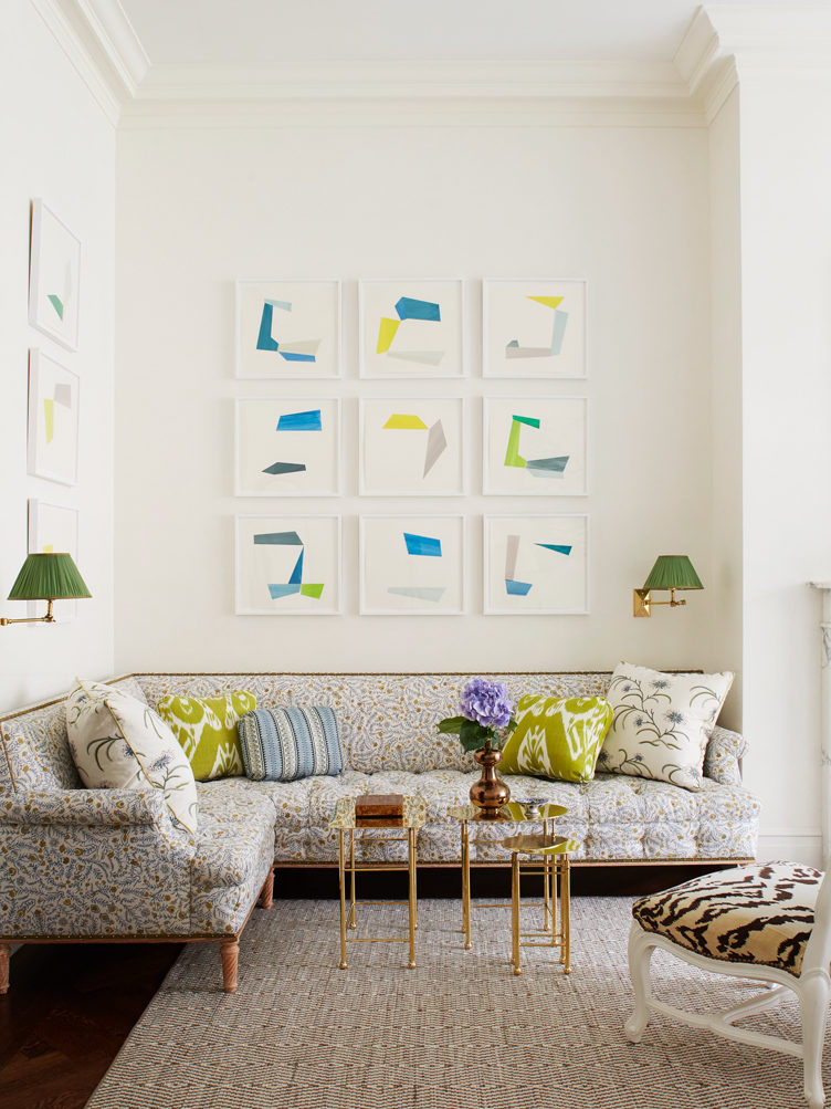 Living room with floral sectional, brass side tables, and gallery wall of abstract prints