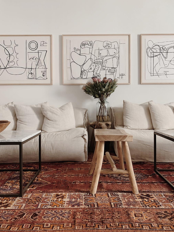 Beachy seating area with framed line drawings and orange textile rug at the Surfrider in Malibu