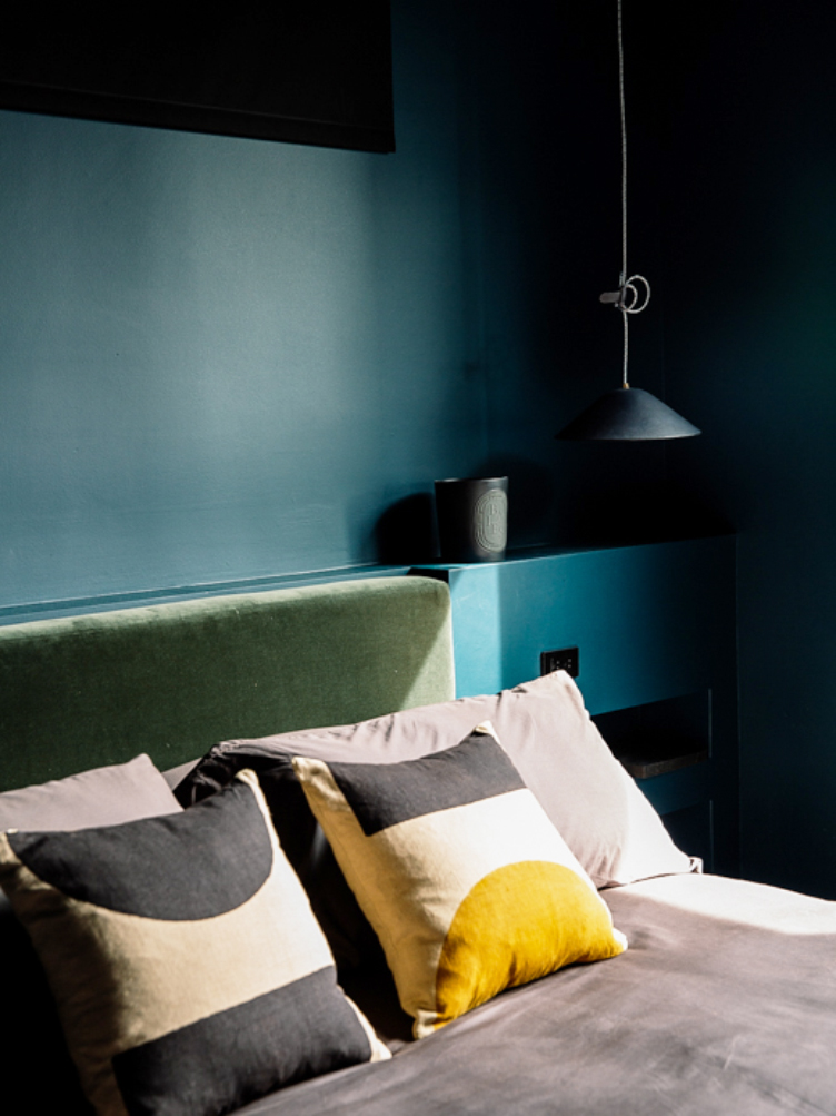 Blue bedroom with green velvet headboard and throw pillows 