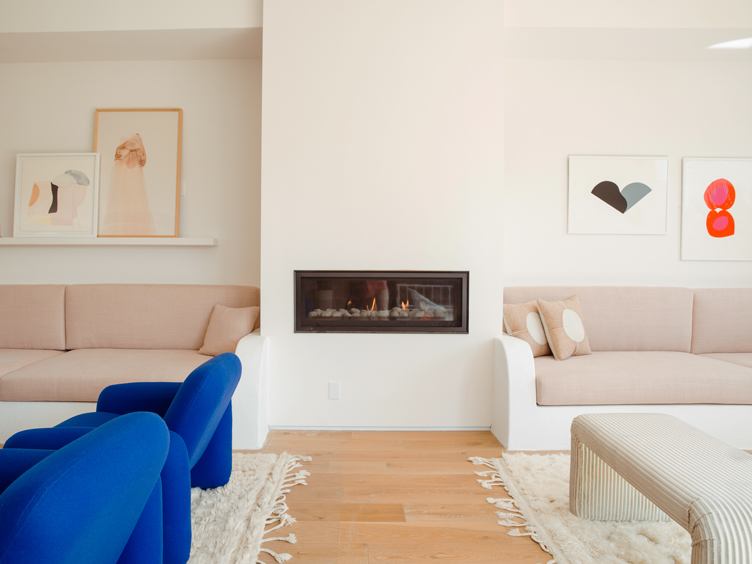 Modern white fireplace with blush couches and framed paintings 