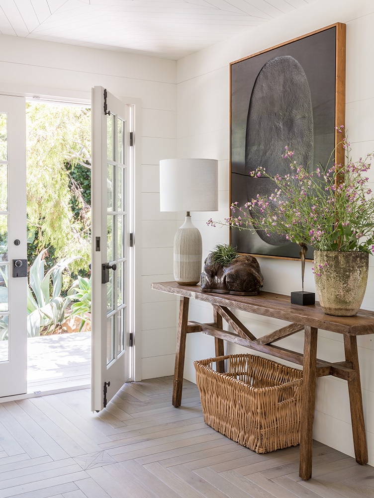 Entryway with natural wood side table, contemporary art, and nature-inspired sculptures.