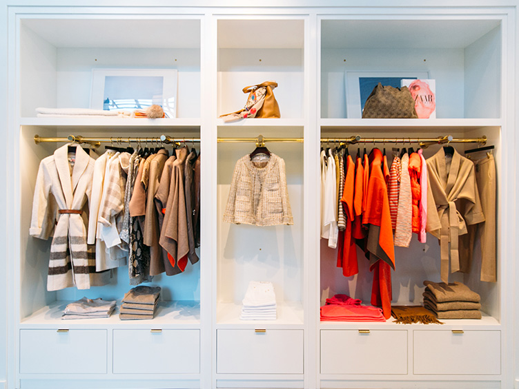 The neutral and orange clothes provide a brilliant contrast to the white drawers and hanging space with gold accents.