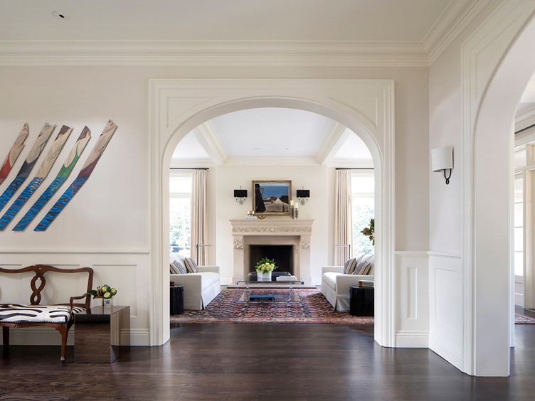 Hallway with abstract art piece looking through an archway to a traditional living room.