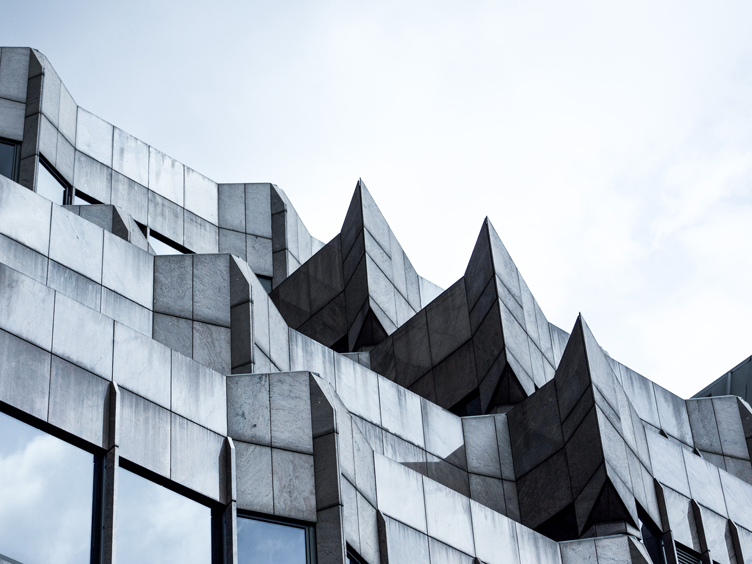 Gray stone brutalist facade of a building with tinted windows