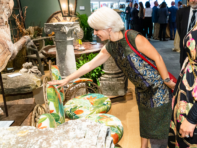 Customers look at floral-printed metal outdoor couch and stone objects