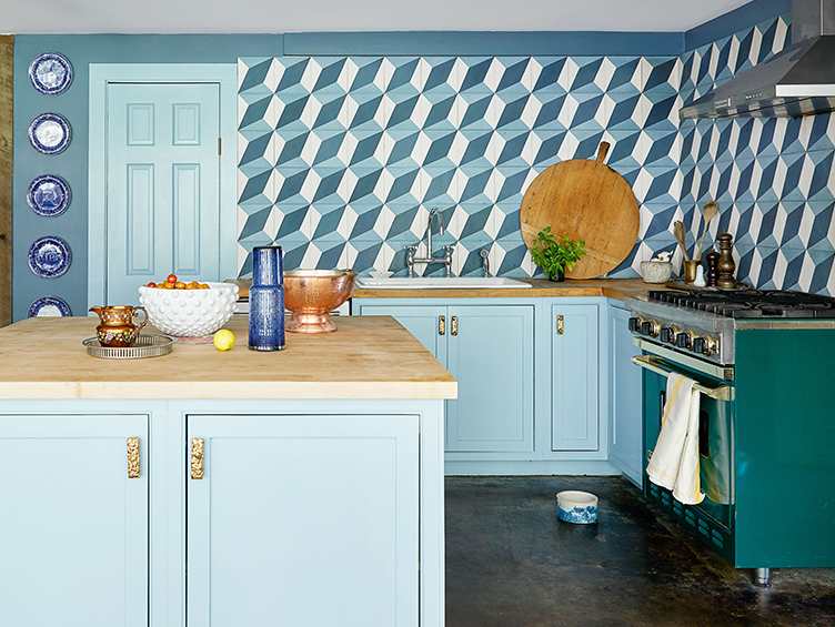 Blue kitchen with geometric patterned backsplash and antique wood cutting board