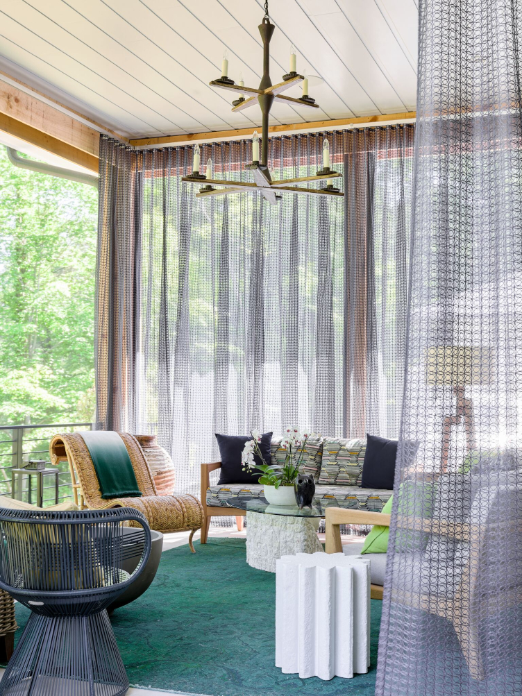 Tish Mills Kirk's design for the Southeastern Designer Showhouse and Gardens features rattan slipper chair, linen curtains, and glass top coffee table. 