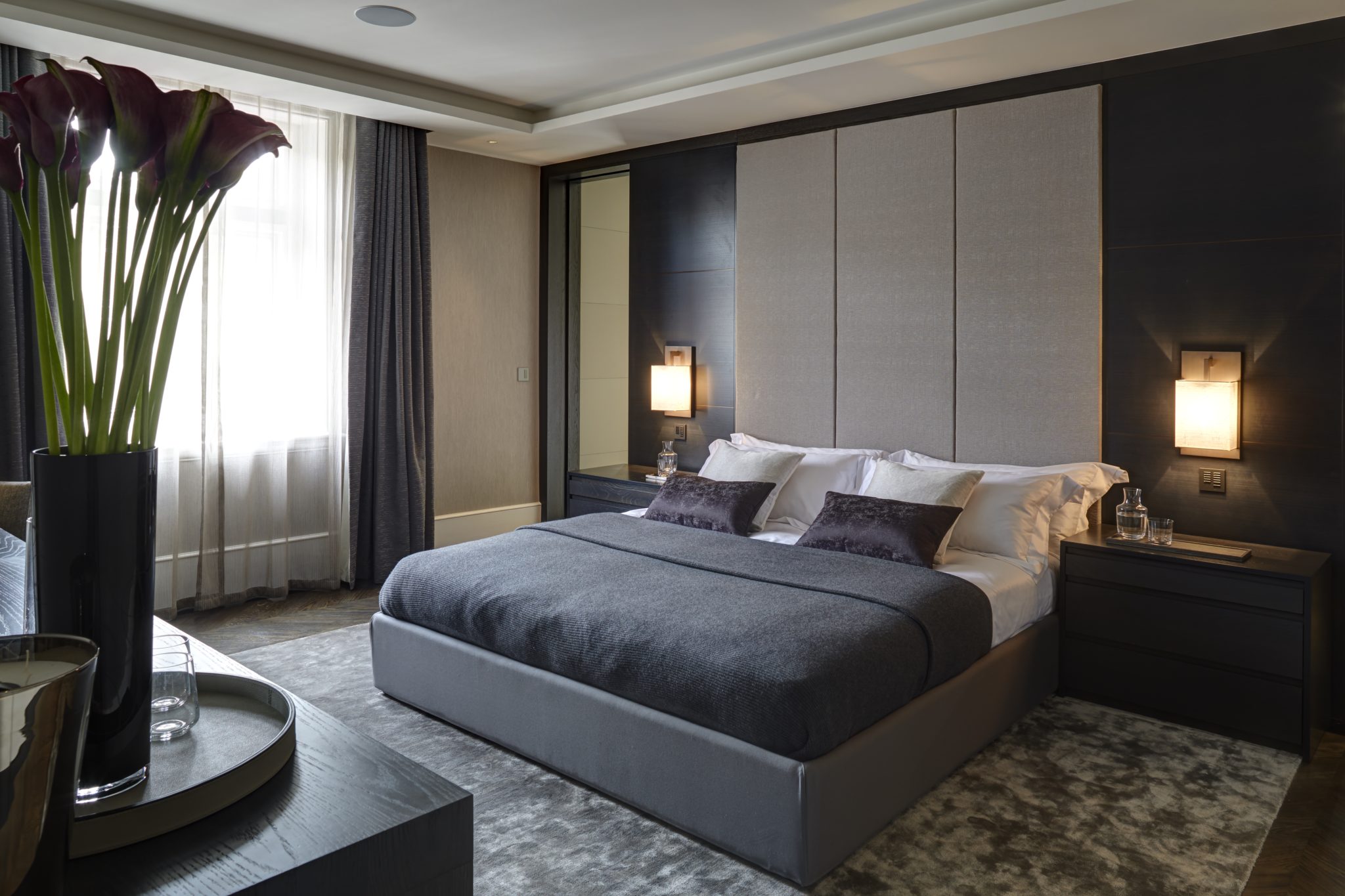 modern bedroom with floor to ceiling headboard and square wall sconces.