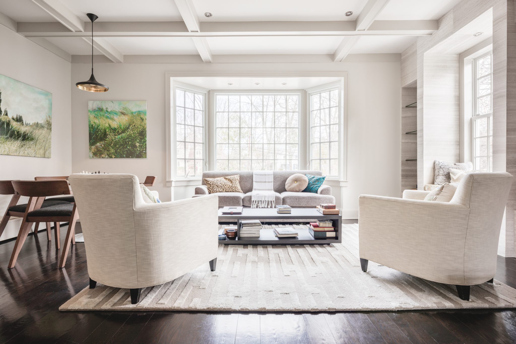 Neutral, layered living room with gold lighting, Knoll table, and mid-century modern chairs by Shelley Cekirge Interiors