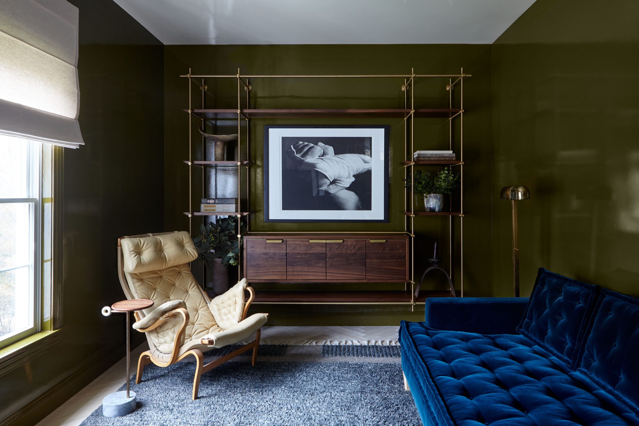 Seating area with glossy green walls and blue velvet couch and tufted cream accent chair.