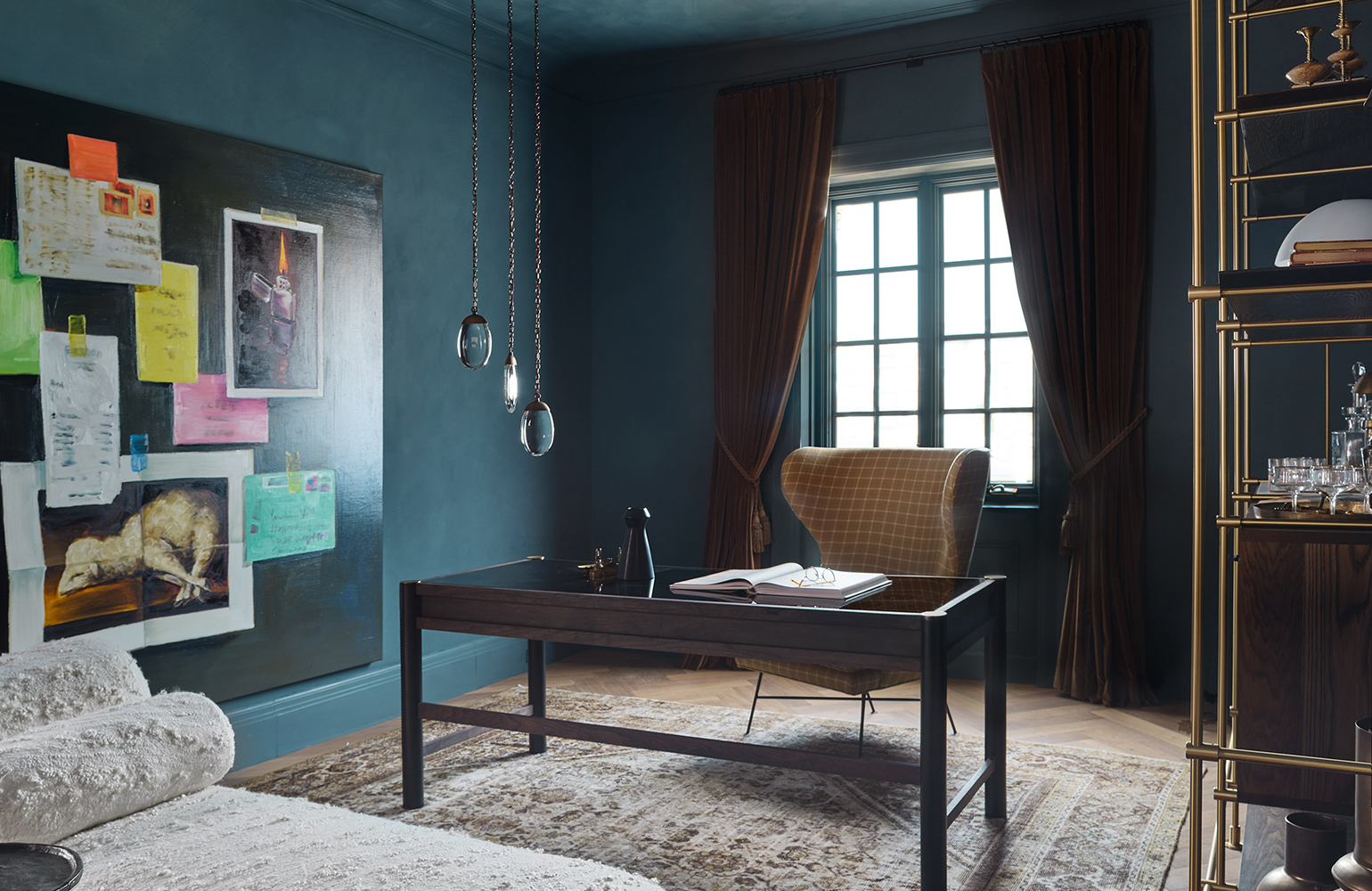 Dark blue office with wood desk, mid-century mustard desk chair and brass shelving.