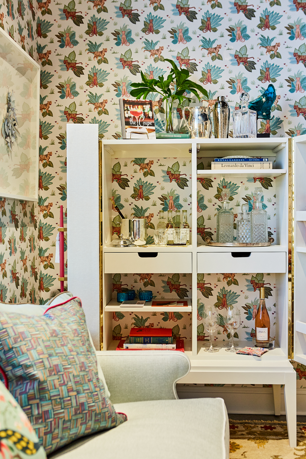 White bar with accent chair in room with jungle themed wallpaper.