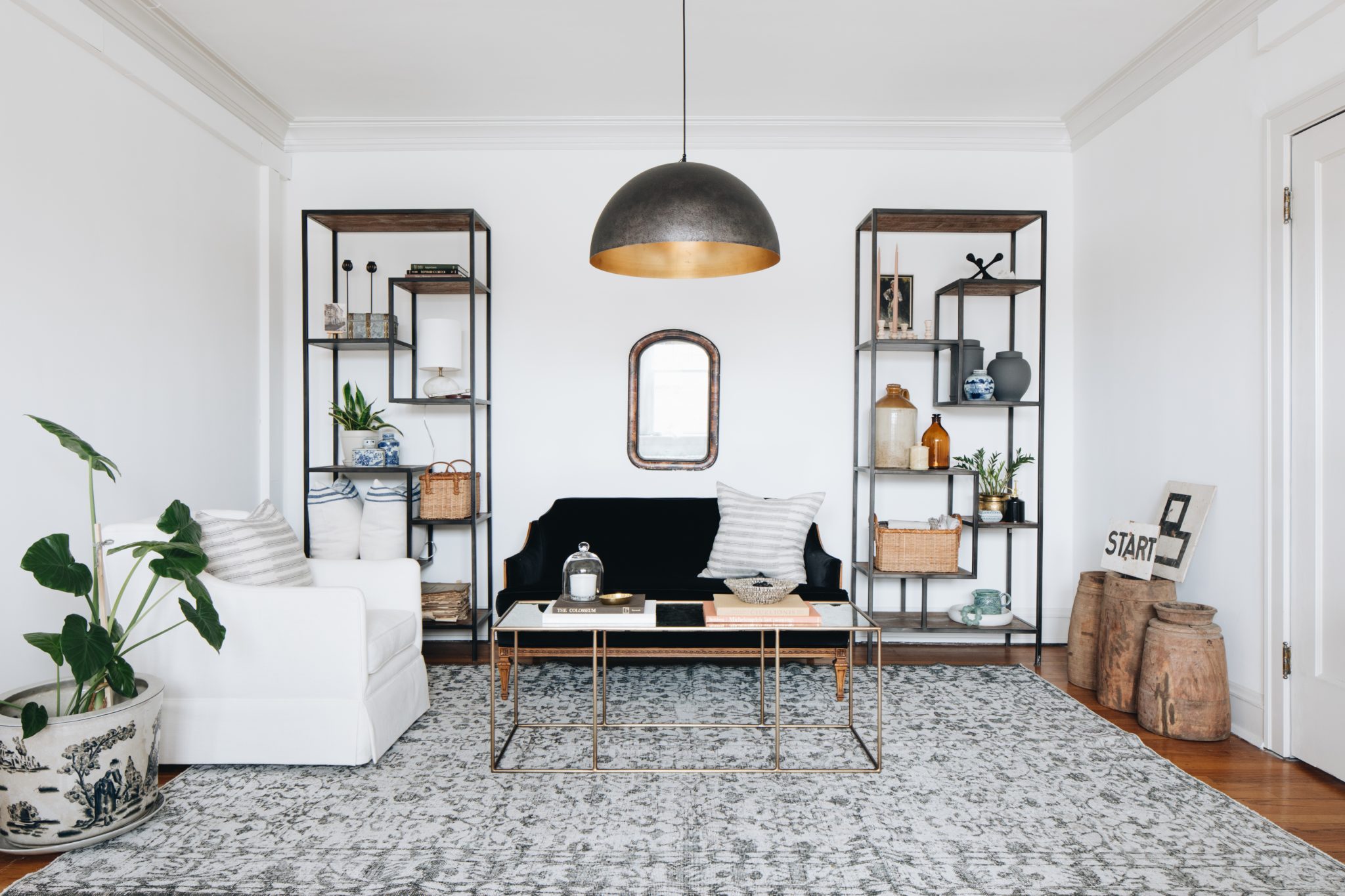 Seating room with black metal shelves, gray rug, black and gold  ceiling light