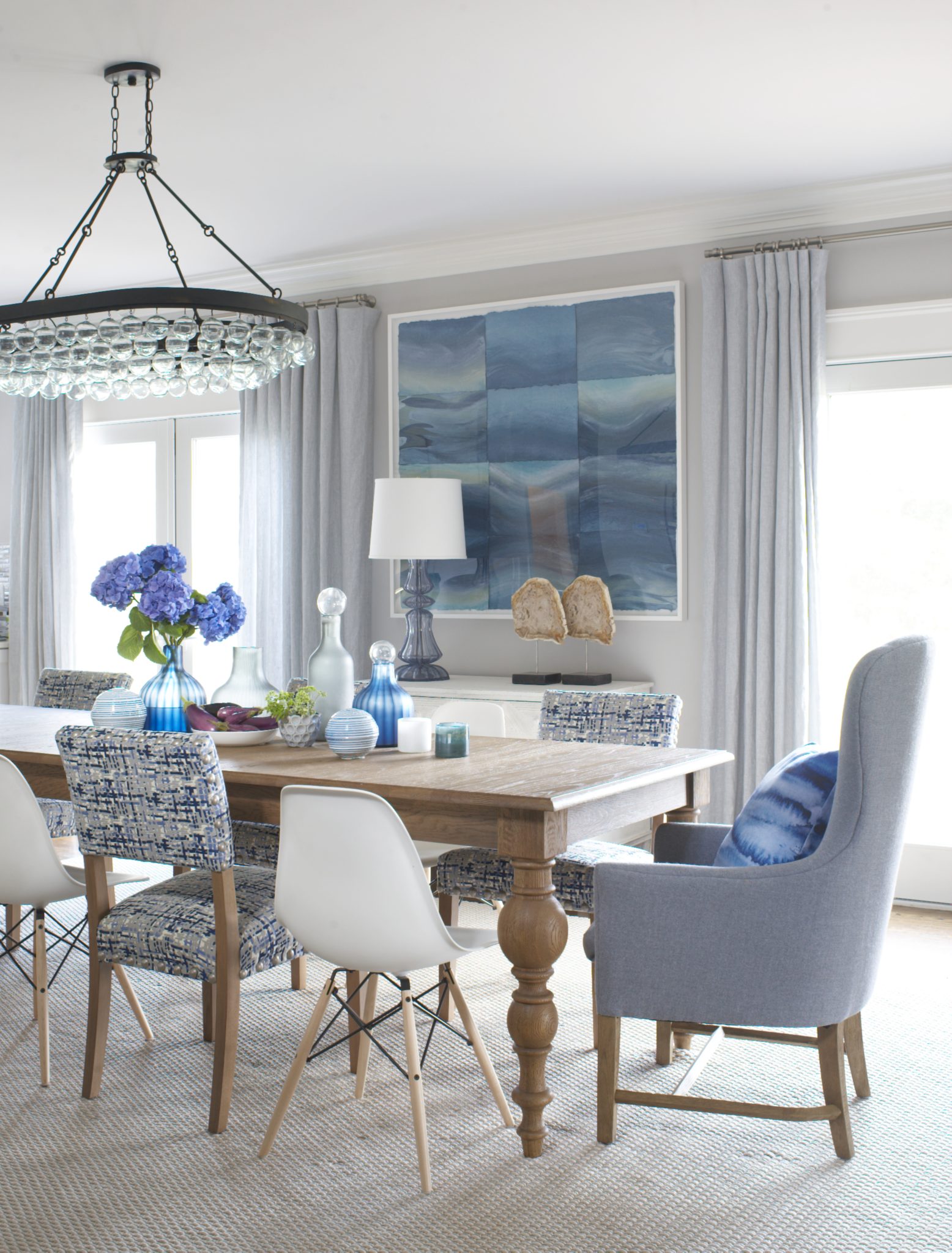 Dining room with mismatched dining chair, glass jars, bottles, vases, and oceanic art piece 