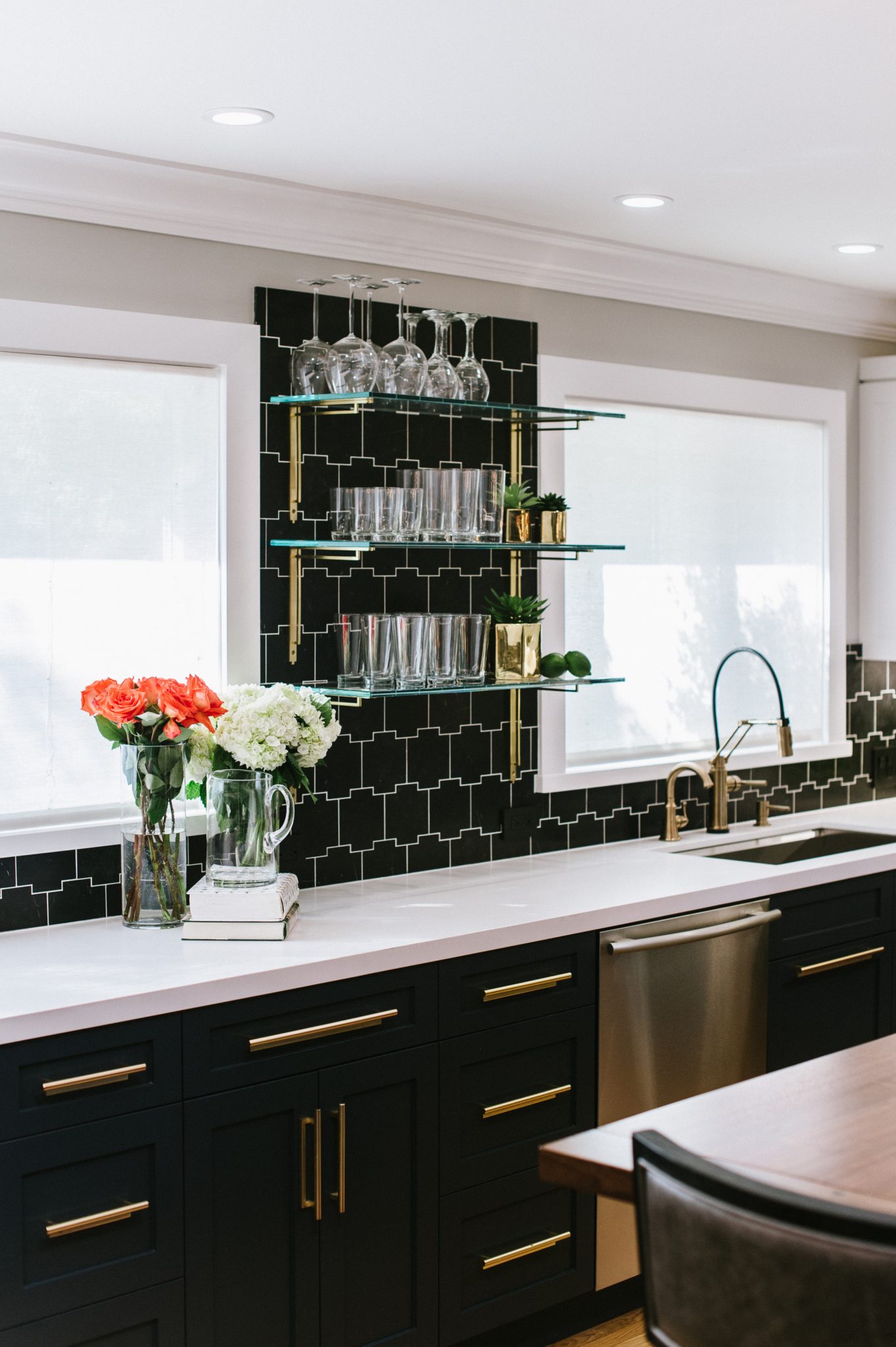 This sleek kitchen features black geometric tiles with white grouting and glass, open shelving.