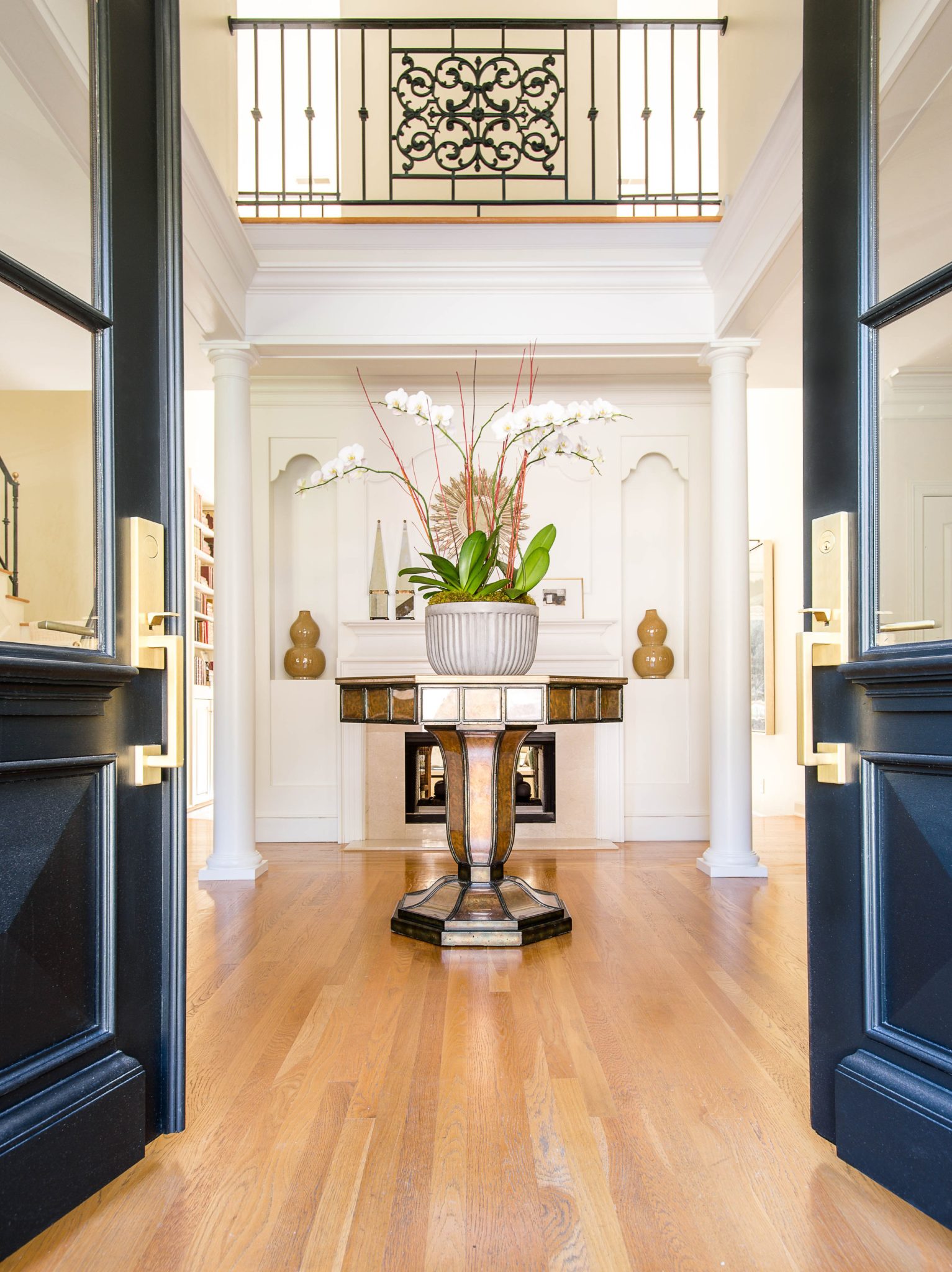 This grand entryway features a deco-style table with black doors and white columns.