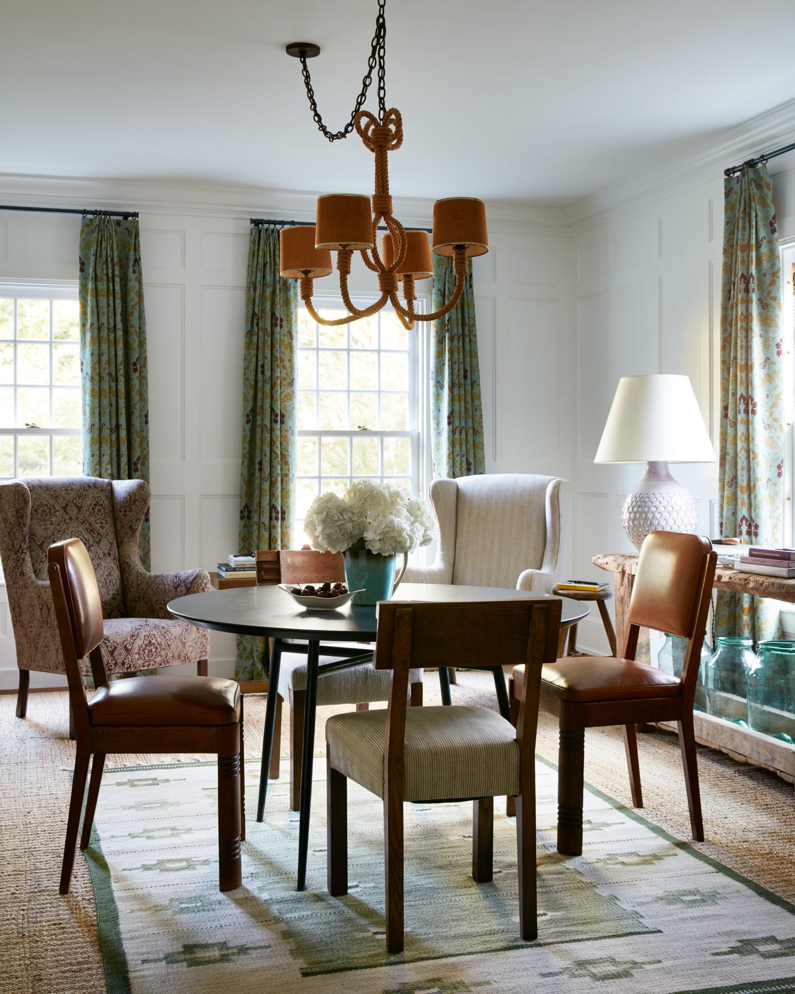 Dining room with mismatched dining chairs and raw wood side table with blue jars