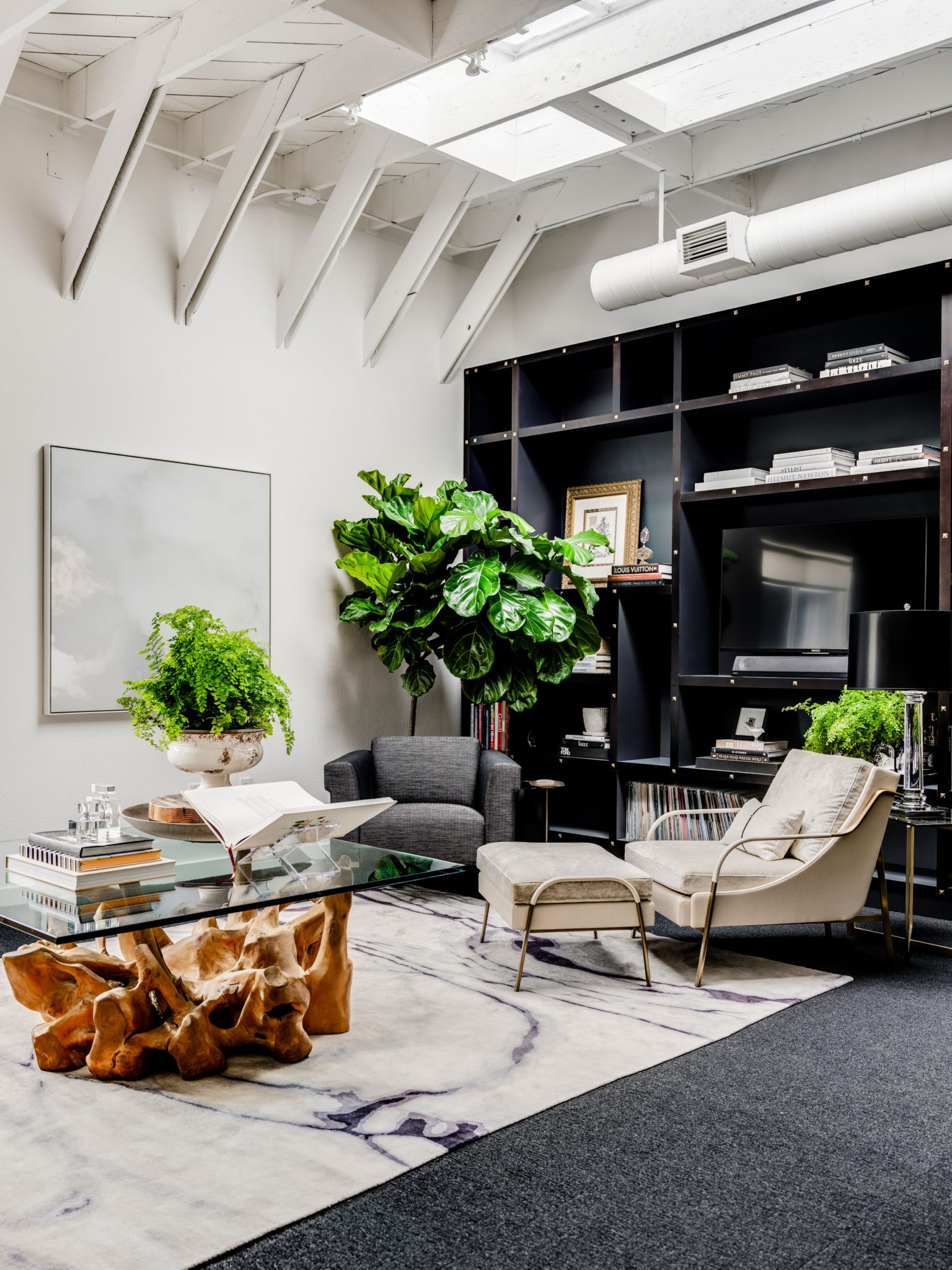 Contemporary living room with black bookshelves and raw wood and glass coffee table