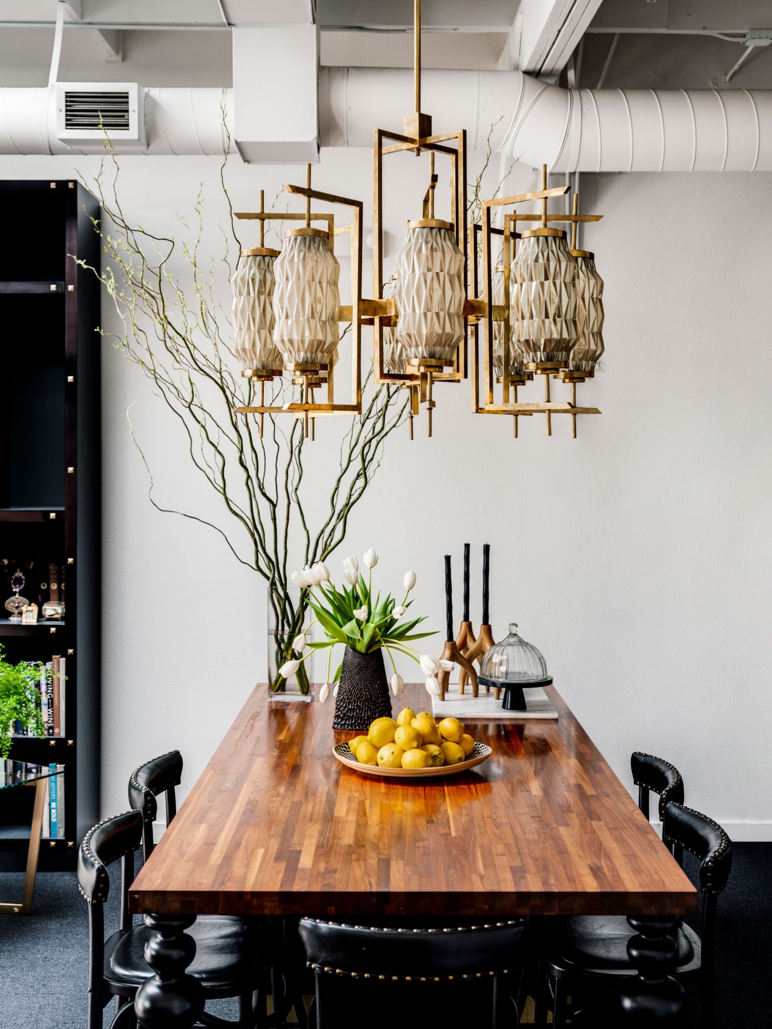 Dining room with wood dining table and black leather dining chairs with brass chandelier 