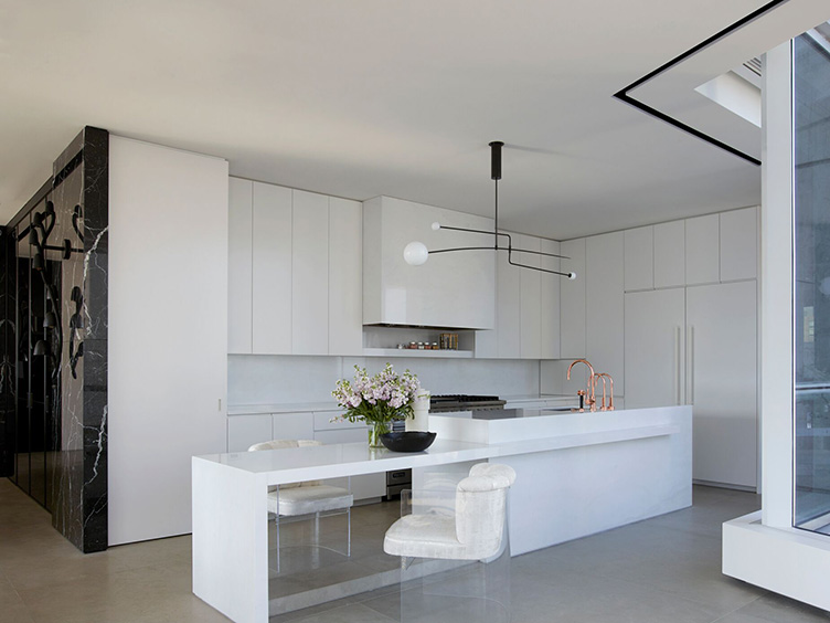 This sleek modern kitchen features  white cabinets and lucite armchairs.