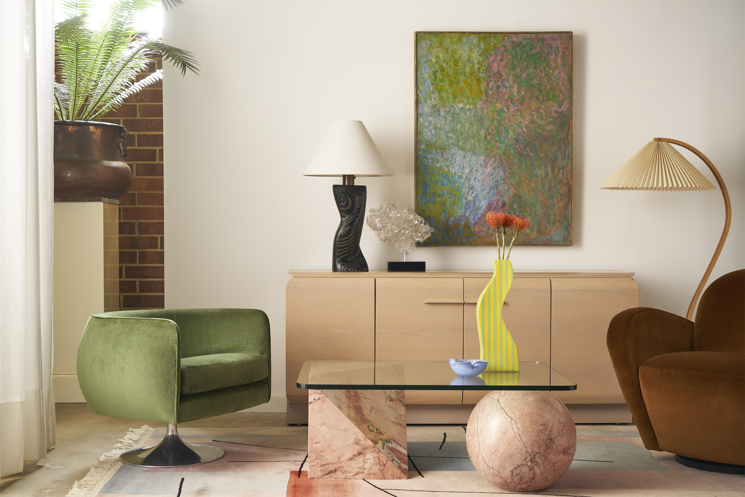 Living room with velvet green swivel chair and structural marble coffee table with glass top.