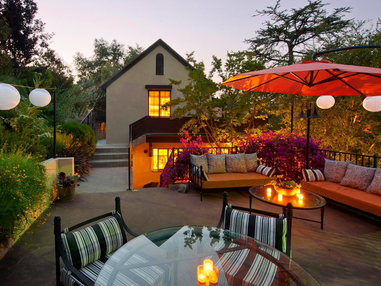 Outdoor area with glass-topped table, striped dining chairs and metal outdoor couches.