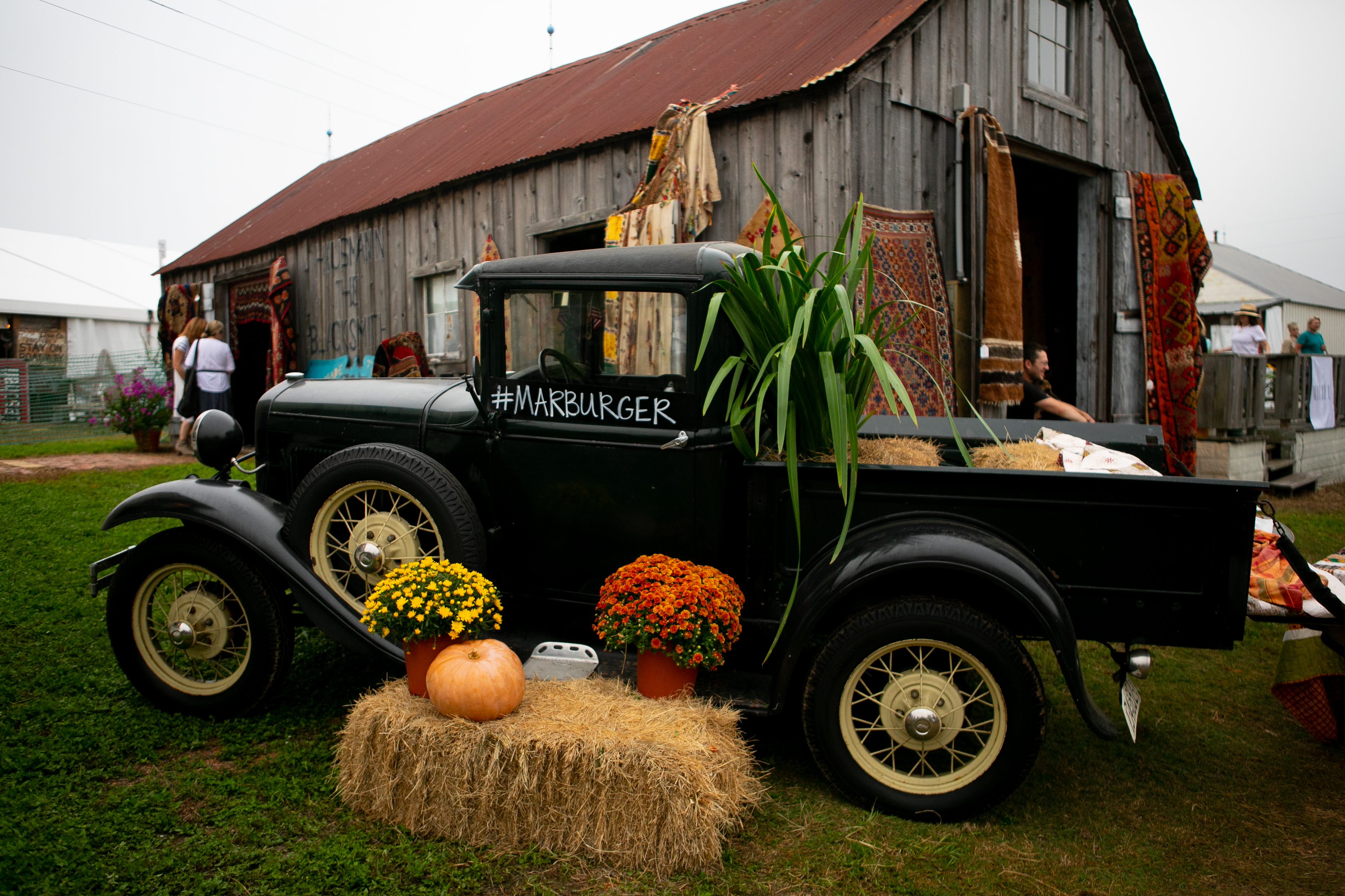 Antique black pick up truck parked outside truck with rugs for sale at round top