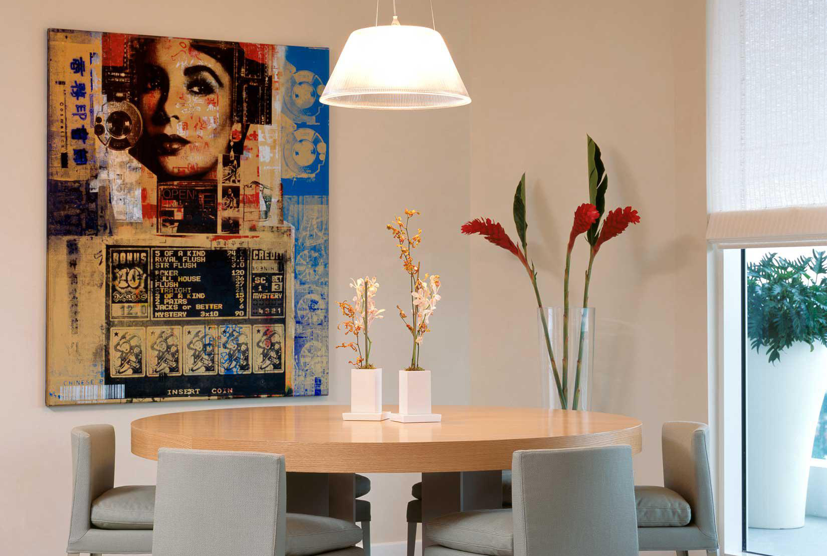 Dining room with round wood table and large hanging collage